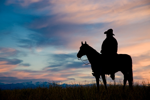 Cowboy on horseback,silhouetted against a dawn sky in Montana