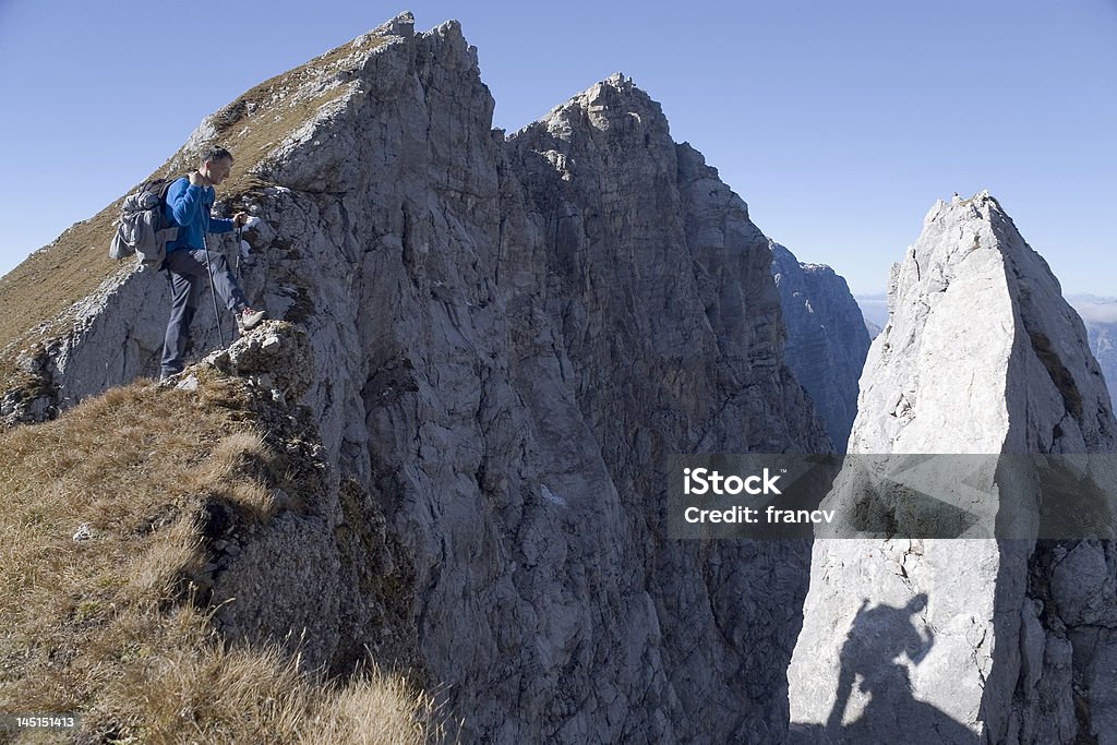 Shadow on the mountains The mountaineer at the edge of cliff is observing his shadow on the rock and also a small bird on the top of the rock at Italian Alps. At The Edge Of Stock Photo