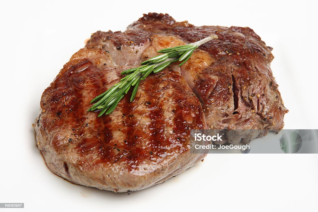Rib-Eye Steak Close-up of a freshly griddled rib-eye steak resting on a white plate Beef Stock Photo