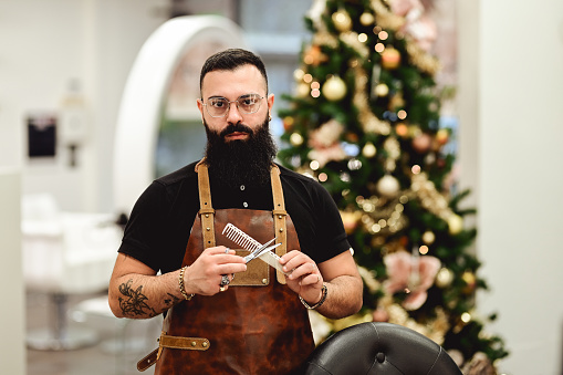 portrait of a confident bearded man holding working tools and looking at camera.