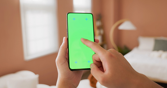 rear view close up asian man holding green screen phone at home