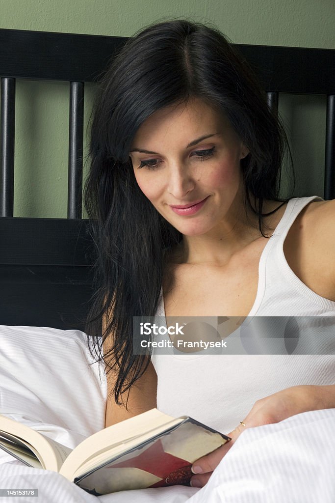 Woman reading book Young woman reading book in bed Adult Stock Photo