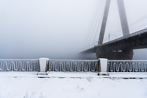 Daugava river embankment on a winter morning. A cable-stayed bridge in the background