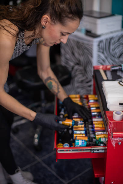 Young female tattoo artist is preparing colors for tattooing. stock photo
