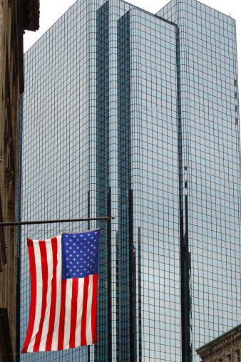 A US flag hanging in front of a glass skyscraper in Boston, Massachusetts.