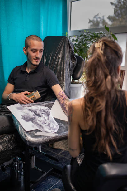 istock Young female tattoo artist is working in her studio. 1451535415