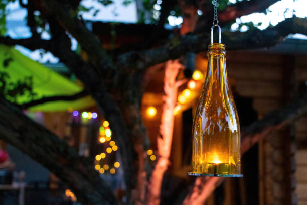 istock Decorative bottle with candle inside hanging in tree in garden at night 1451538218