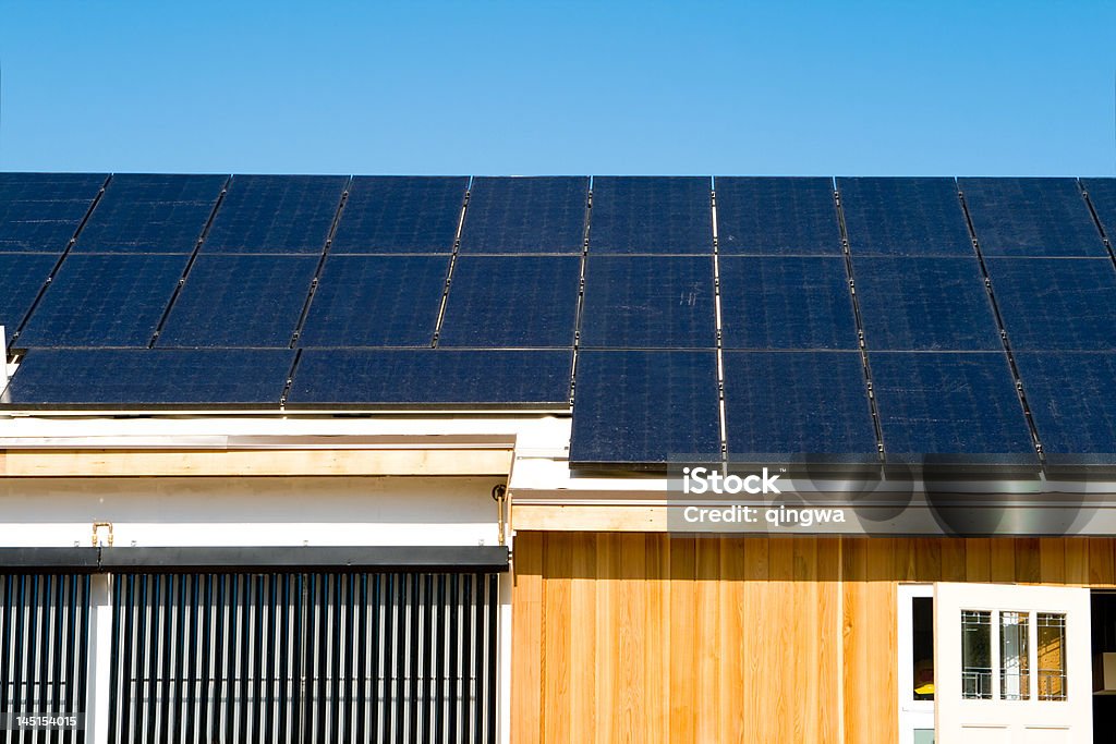 Современный дом с использованием фотоэлектрических солнечных панелей на крыше, охватывающих небесно-голубой - Стоковые фото Вне сети роялти-фри