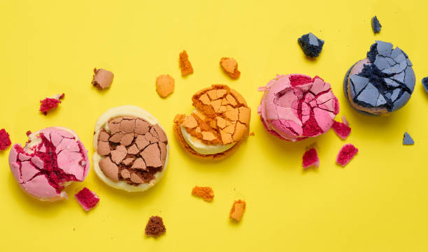 istock Broken round macarons with crumbs on a yellow background, delicious dessert, top view 1451541574