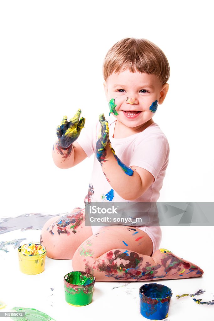 Happy Girl Painting Delighted baby girl painting with color tubes. Isolated on white background. Child Stock Photo