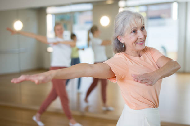 Senior woman performing contemporary dance in studio Senior woman performing contemporary dance during group training in studio. contemporary dance stock pictures, royalty-free photos & images