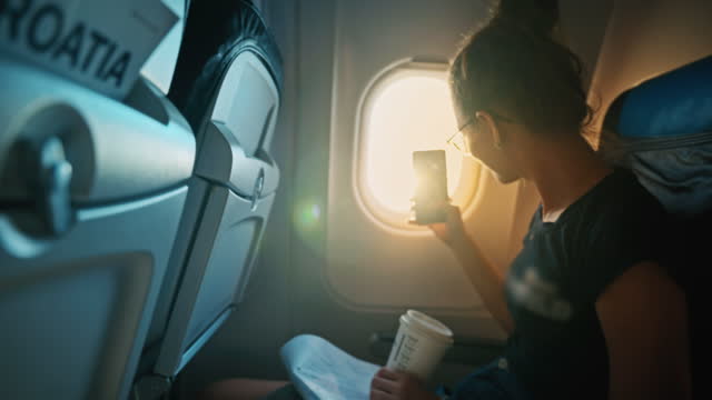 SLO MO A young girl takes a photo through window during an airplane flight and shows the picture to the camera