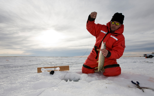 A man with a northern pike on a frozen lake