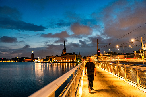 Rear view of a person walking the empty streets of Stockholm on a summer night