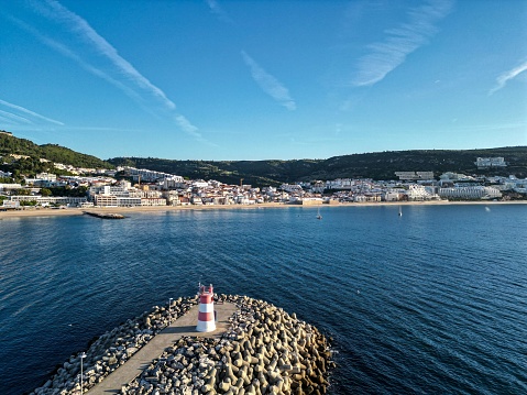 A scenic view of a tranquil beach with traditional buildings on the coastline in Setubal, Portugal
