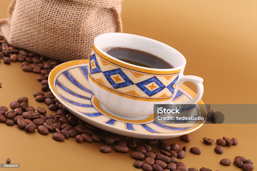 Coffee cup and beans Cup of coffee, canvas bag full of coffee and lots grains of coffee on gold background Bag Stock Photo