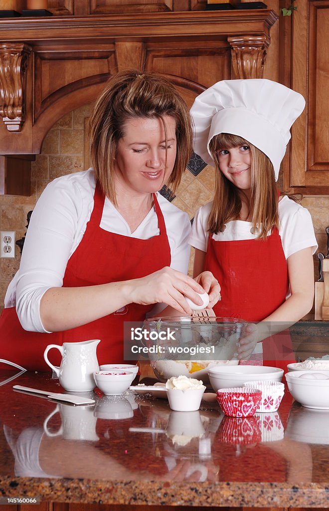 Baking together A cute young girl and her mother baking cupcakes together Baking Stock Photo