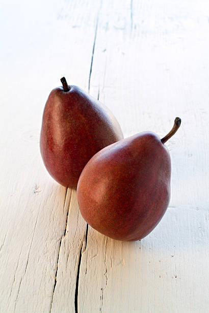 Two Red Pears Two Red Pears on white wooden surface forelle pear stock pictures, royalty-free photos & images