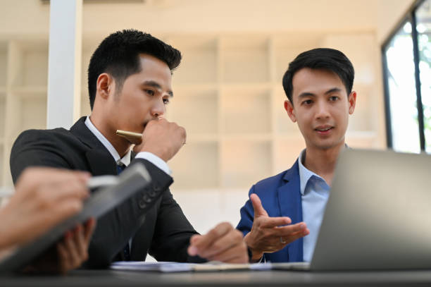 istock Two concentrated and smart Asian businessmen talking, working on their project together. 1451611856