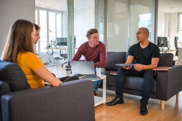 istock Discussion Between Businessmen who are Seated on a Sofa and Using Wireless Technology 1451614557