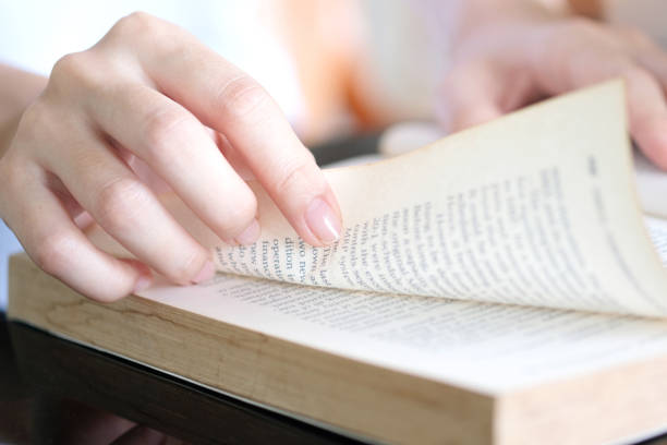 istock Reading. A woman opens a book. she is reading a book in the library to study and spend their free time studying 1451621495