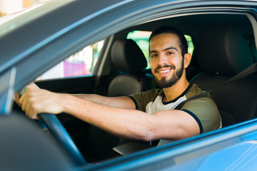 Handsome latin man smiling making eye contact while working as a driver for a ride share service