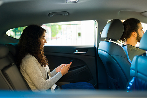 Happy woman passenger using the mobile app of a ride share service on her smartphone