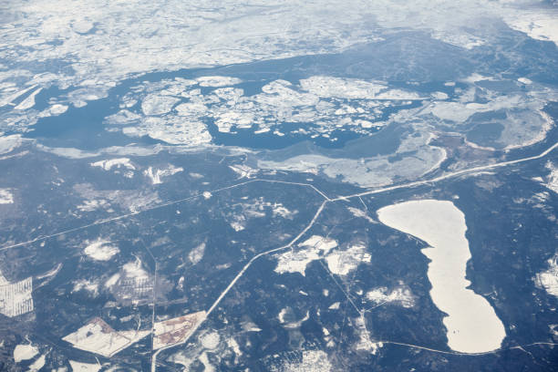 istock Aerial view from airplane window over clouds top to snow covered rivers, fields and roads 1451630633
