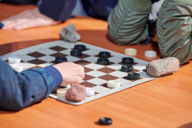 istock Outdoor draughts competition on paper checkerboard on table, close up players hands 1451630661