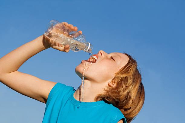 Thirsty child drinking out of a water bottle stock photo