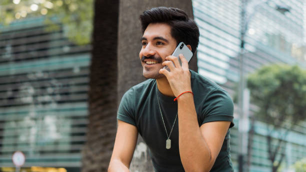 istock Latin man with mustache smiling, sitting on a bench making a phone call. 1451643129