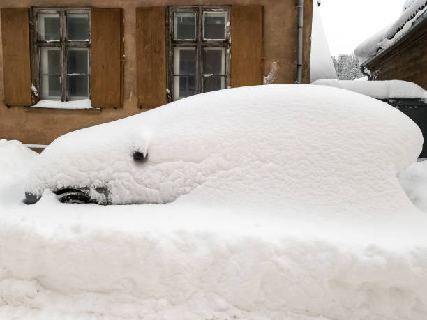 The car in the parking lot is completely covered with snow. Problems after heavy snowfall.