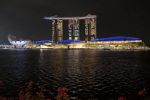 Artscience Museum and the Marina Bay Sands at night, an integrated resort fronting Marina Bay in Singapore. The complex includes three towers height 207 mt, topped by the Sands Skypark, a skyway connecting 340-metre-long large platform .