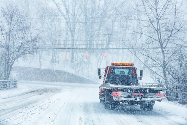 Flat Bed Tow Truck Driving in Blizzard Snow Storm stock photo