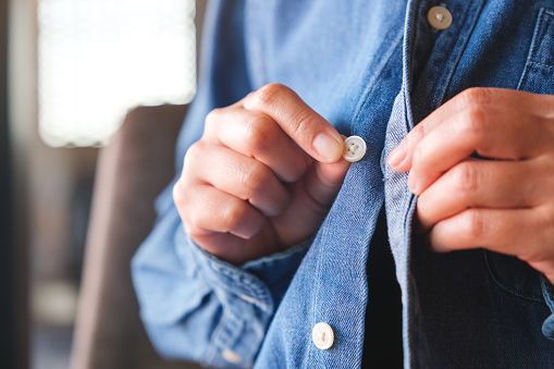 Closeup of a woman buttoning her jeans shirt