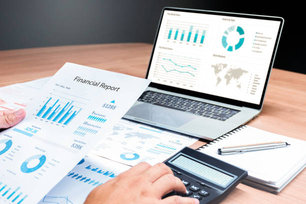 istock Businessman hand holding financial report document with slide show presentation on display laptop and calculator ,notebook on table in meeting room 1451661831