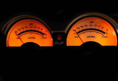 decibel meter of a sound amplifier illuminated orange on black background