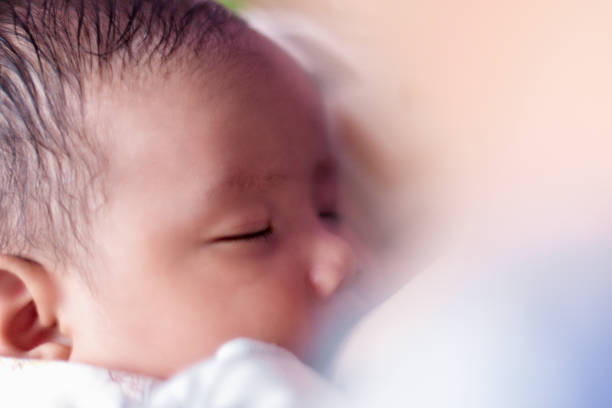 Young baby playing with mother and sleeping after breastfeeding - Stock photo