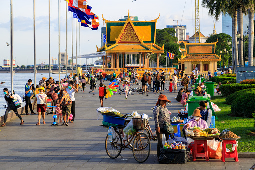 Phnom Penh, Cambodia - November 30, 2022: People walking in the evening along the Mekong River waterfront esplanade in Phnom Penh, Cambodia.