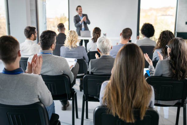 istock Back view of entrepreneurs applauding on education event in board room. 1451681018