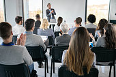 Back view of entrepreneurs applauding on education event in board room.