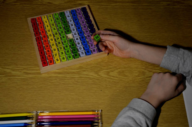 istock schoolboy draws with colored crayons and assembles a knowledge kit where there are numbers with multiples on wooden blocks. multiplication and division can be taught in a fun, playful way at school 1451684077