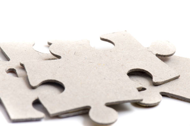 istock Close-up on jigsaw puzzle pieces, blank white paper jigsaw puzzle elements linked together and separate. 1451685795