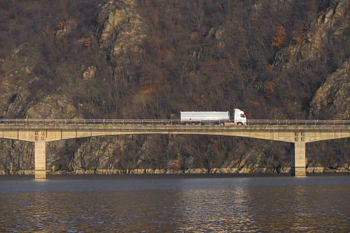 Tanker, truck that transports compostables crosses the bridge over the water.