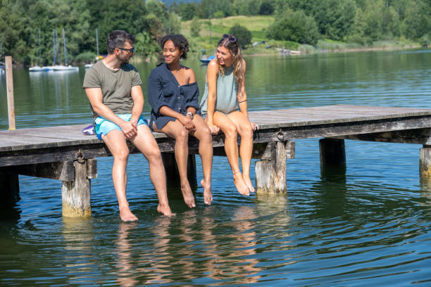 istock Friends having nice chilled conversation while sitting on a wooden pier with feet dangling down 1451695786