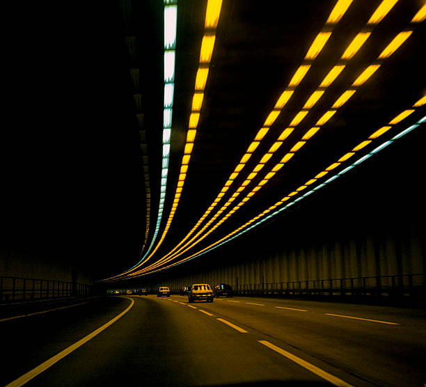 cars on road in tunnel with lights overhead