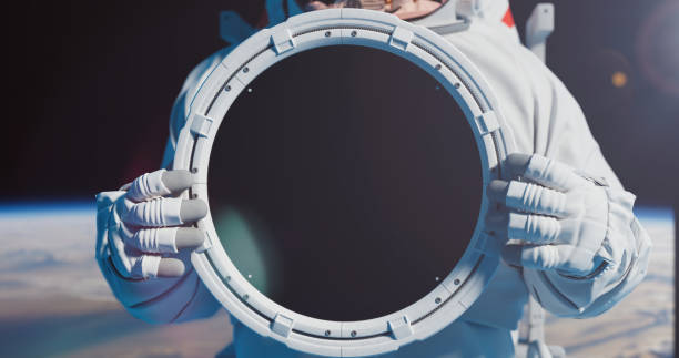 An astronaut with a round plate with trackers  for your title. Astronaut against the Earth. Spacemman holding a round plate with chromakey in his hands