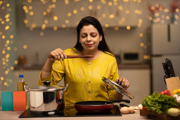 Portrait of Indian woman enjoying while cooking meal in the kitchen. stock photo stock photo