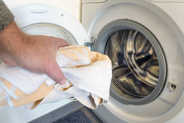 istock Light-colored clothes are washed in the washing machine. man holding a towel 1451707490