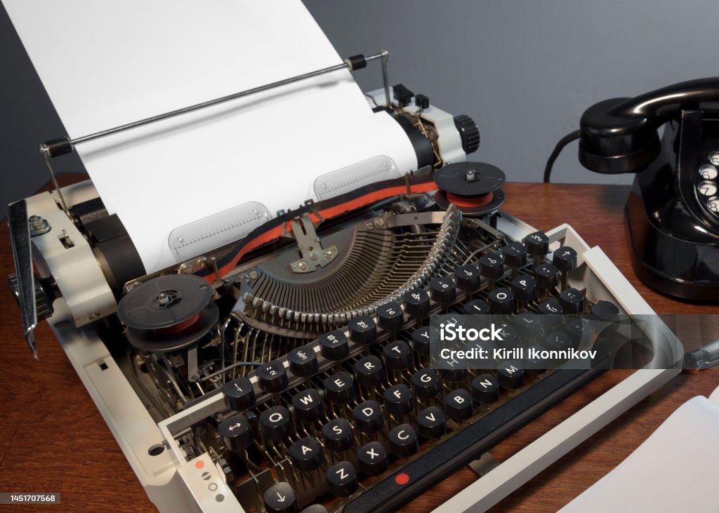 Retro old typewriter from 70s with paper blank on wooden table. vintage. Place for text Article Stock Photo